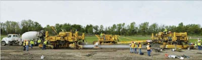 A paving train constructing R21 research sections along I-94 at MnROAD:From the left, a mixer truck, first paver, material transfer device and second paver. Photo courtesy of Tompkins, Vancura, Rao, Khazanovich, Darter