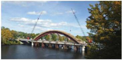 The contractor is placing the concrete for the arch rib for the new bridge. Note the two in-water piers and the NEBT approach span that have already been completed along with the falsework.