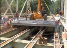 Placement of fiber-reinforced polymer (FRP) deck panels on steel girders of a 125-foot through-truss bridge at Maryland S.R. 24, north of Baltimore, near Rock Creek State Park.