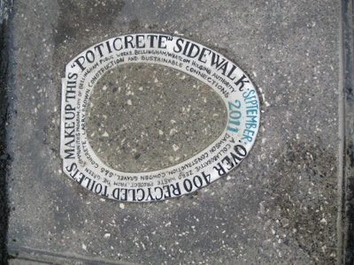 A toilet seat in the sidewalk showing that more than 400 recycled toilets compose the sidewalk