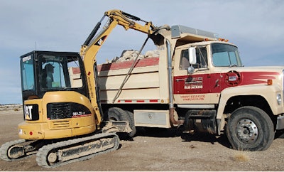 At a rural residential jobsite, a Caterpillar 303.5C CR compact excavator loads the truck that started it all – a 1972 Ford.