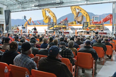 A view from the back of a Ritchie Bros. auction theater in Chilliwack, B.C., Canada. Most mobile equipment is driven over a ramp in front of a crowd of bidders