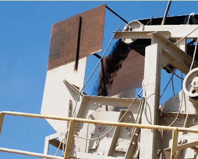 In central Texas, crushed recycled asphalt shingles (RAS) are conveyed to an asphalt drum.