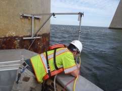 Engineer deploying sonar head attached to bracket system on pier