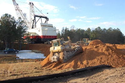 A trio of dozers, a motor grader and padfoot compactor race to build up a 12 foot berm of dirt to protect the roadway from Mr. Tom’s oncoming load.