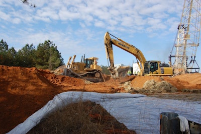 An excavator pulls off the straw bales that served as the first line of protection for the road.