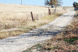 A clogged corrugated drainpipe under this Texas road results in water flowing across it, eroding the surface and creating a ford in wet weather.