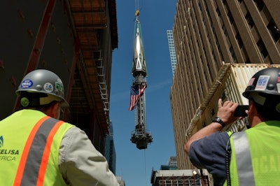 Construction workers watch as the spire is hoisted atop the World Trade Center. /Credit: EPA