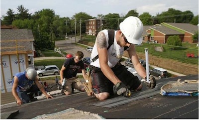 Jonathan Silke cuts shingles on a roof in Des Moines. Credit: Bryon Houlgrave/The Des Moines Register