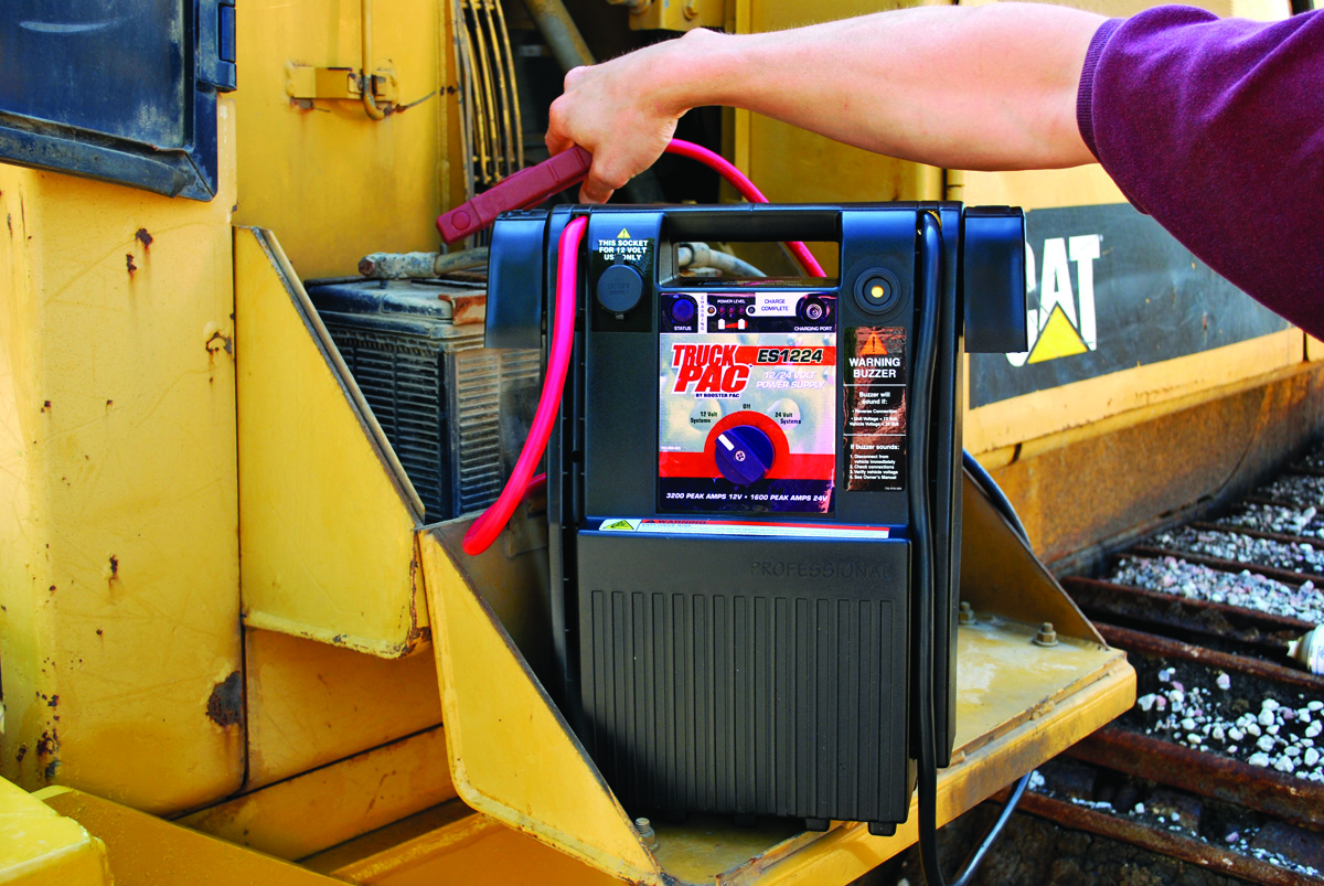 Technician jump starting a Caterpillar excavator with a Clore Automotive ES1224 Battery Jump Starter
