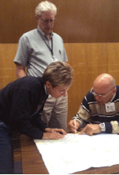 Bill Farnbach with Caltrans (standing) looks over some preliminary plans for a long-life asphalt pavement design during a meeting with Rita Leahy of CalAPA (left) and Bob Humer with the Asphalt Institute.