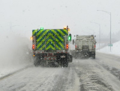 Plows push snow on to the shoulder of Interstate 77, resulting in a snow cloud several feet high.