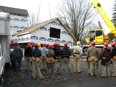 Students in the Fredrick County (Maryland) Career and Technology Center carpentry program observe a garage craning on the site of the program’s annual project house.
