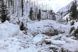 An ITD worker (in orange) stands where road should be. An estimated eight avalanches have occurred in the past few days on Highway 21 in Idaho, completely covering a 12-mile portion of the road. (Photo Credit: ITD, via Boise State Public Radio)