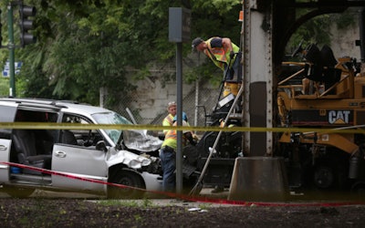 A crew works to dislodge a minivan from a paver after a crash in Chicago Saturday morning that killed one construction worker. Credit: Abel Uribe/Chicago Tribune