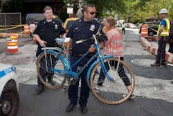 A New York City police officer carries away a woman’s bike after she was hit by a cab.