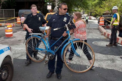 A New York City police officer carries away a woman’s bike after she was hit by a cab.