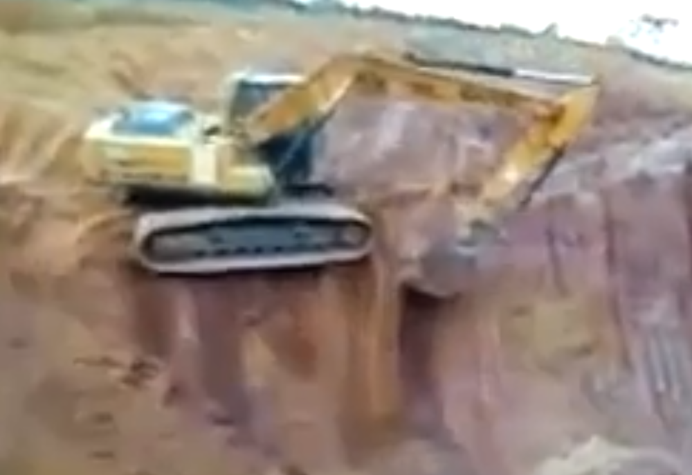 Excavator topples off bench