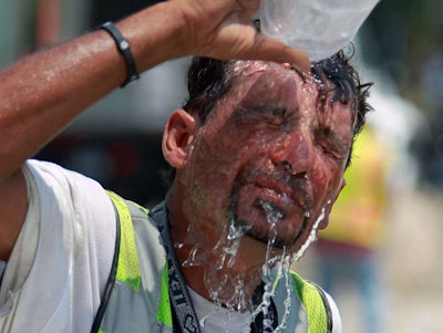 Construction worker pouring bottle of water over head