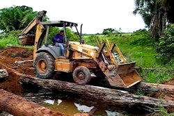 Backhoe crosses water on bridge made of logs