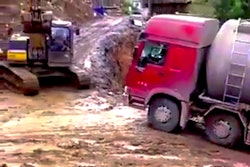 Excavator pulls truck up hill