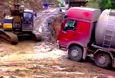 Excavator pulls truck up hill