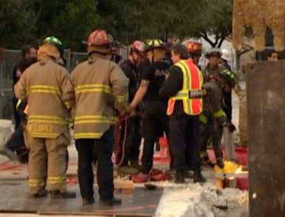 In this still from KENS 5 video, firefighters can be seen gathering near the trench the worker was rescued from.