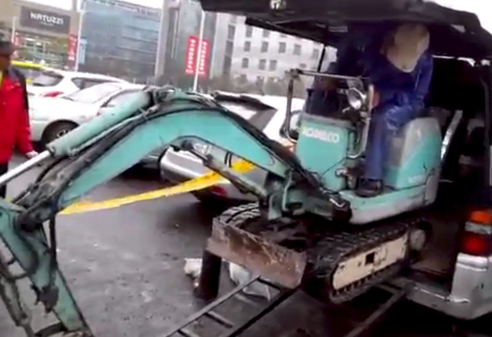 Guy loads excavator into minivan