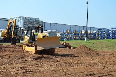 A Cat demonstrator shows how easy it is to maintain a course with stable blade and slope assist by taking a drink of water with his right hand as the dozer moves forward.