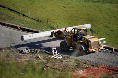 A loader continues to unload pipe from a flat-bed trailer after one of the pipes crushed and killed a worker on the site. Credit: Beth Schlanker/Press Democrat