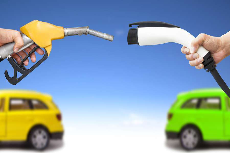 Electric Car And Gasoline Car Concept. Hand Holding Gas Pump And