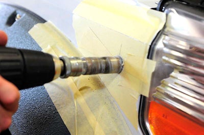 Drill pilot hole, then use 1-inch hole saw to cut mounting hole in fender.