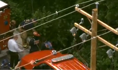 Rescue personnel work near where the road gave way.