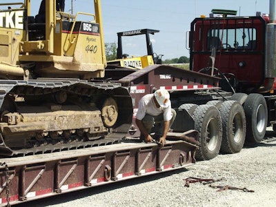 Worker Securing Cat Dozer To Trailer Heavy Haul