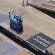 A scissor lift loads itself onto a truck at a United Rentals yard using autonomous technology developed by 5D Robotics.