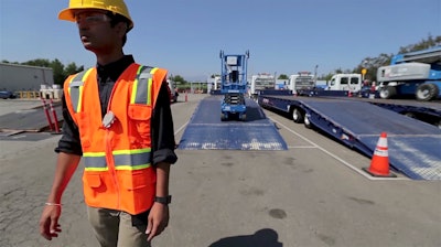 A scissor lift follows a United Rentals employee off of a truck. 5D Robotics’ ultra wide band (UWB) radio technology allows machines to “see” and respond to human instruction thanks to tags worn or carried by employees.