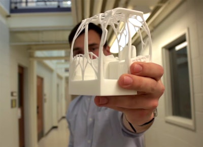 Andrew Peterman holds a 1/16 scale printing of his team’s design for the excavator cab.
