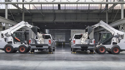 Skid-Steer loaders drop approximately 825 pounds of landscaping blocks into the beds of a 2016 Chevrolet Silverado and a 2016 Ford F-150 (from left to right).