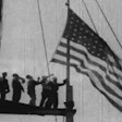 Workers raise the American flag during construction of the Empire State building.