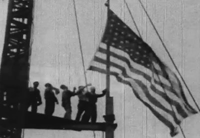 Workers raise the American flag during construction of the Empire State building.