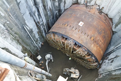 Crews working for Seattle Tunnel Partners fill in the pit used to access and repair Bertha, the SR 99 tunneling machine on Dec. 14, 2015. Sand was delivered into the pit through the flexible pipe on the left, and was then spread out and compacted by crews inside the pit. Photo credit: WSDOT via Flickr