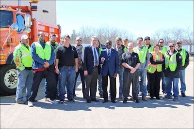 Riverland Community College President Adenuga Atewologun, center, holds the keys to the 2000 Sterling snowplow donated to the college’s truck driving program by the Minnesota Department of Transportation. MnDOT District Engineer Jeff Vlaminck is directly left and Jonathan Rymer, the truck driving program director is directly right of Atewologun. Students and staff of the program gathered for the photo by the snowplow. (Riverland Community College)
