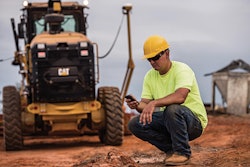 Worker contractor using phone Cat Caterpillar machine