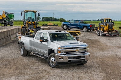 A 2017 Chevy Silverado 3500 with a John Deere 244K wheel loader in two, sits in front of a 2500 hauling a Deere 324E skid steer. All photos by Jessica Walker, courtesy of Chevrolet.