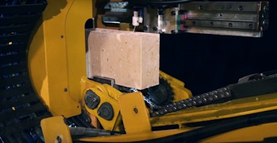 The Fastbrick Hadrian X robotic bricklayer applies a line of mortar to a brick before placing it.