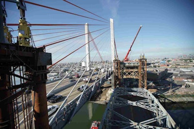 The old (right) and new (left) Kosciuszko Bridges pictured side-by-side as the Skanska-led joint venture team lowers the former Kosciuszko Bridge onto two barges below. (Skanska USA)