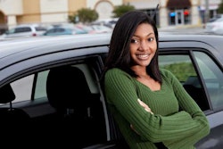 African American teenage girl leaning on car