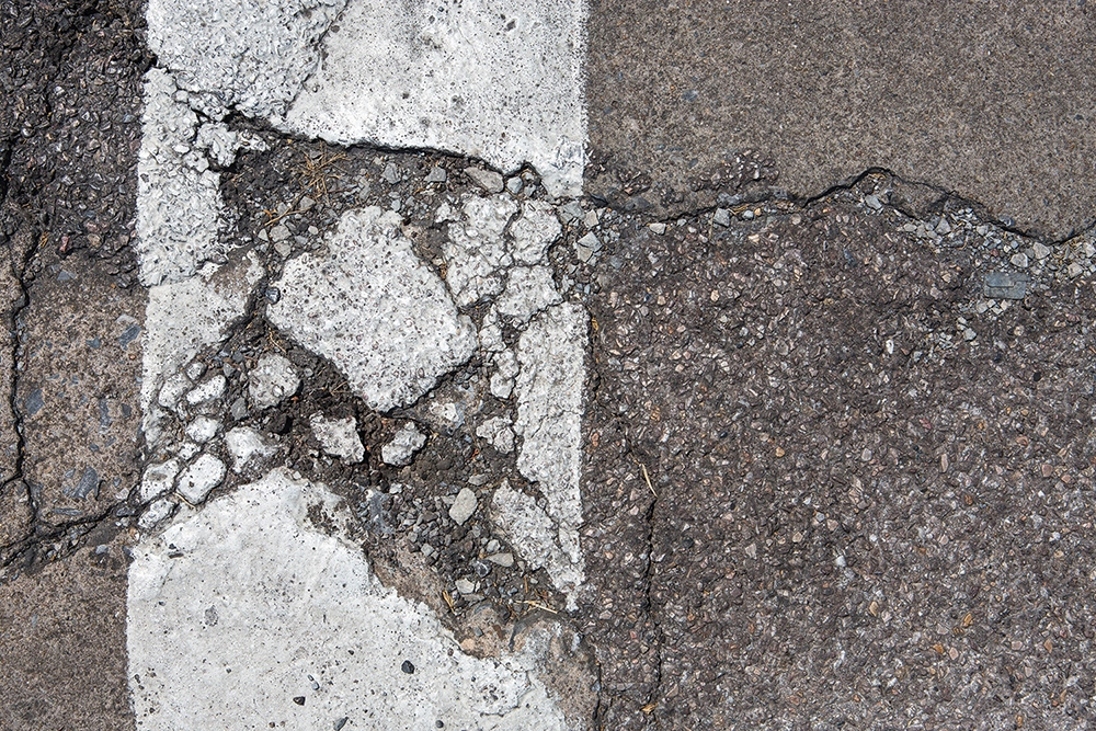 Stock road damaged crumbled crumbling asphalt