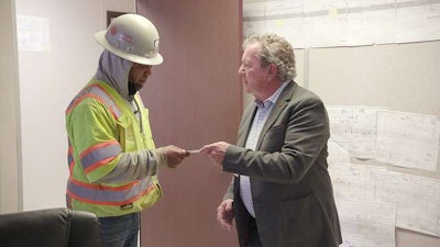 Art Daniel, right, presents a check to one of 83 construction workers who suffered damage from Hurricane Harvey.