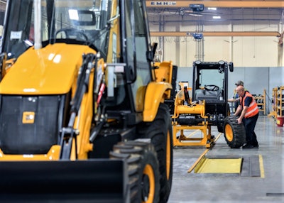 A backhoe is seen in the foreground at JCB’s Savannah, Ga., facility as assembly line workers manufacture a 505-20TC telehandler. Production of the telehandler will replace that of backhoes at the facility in September.